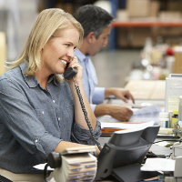 Una mujer sonriente hablando por teléfono en su oficina.